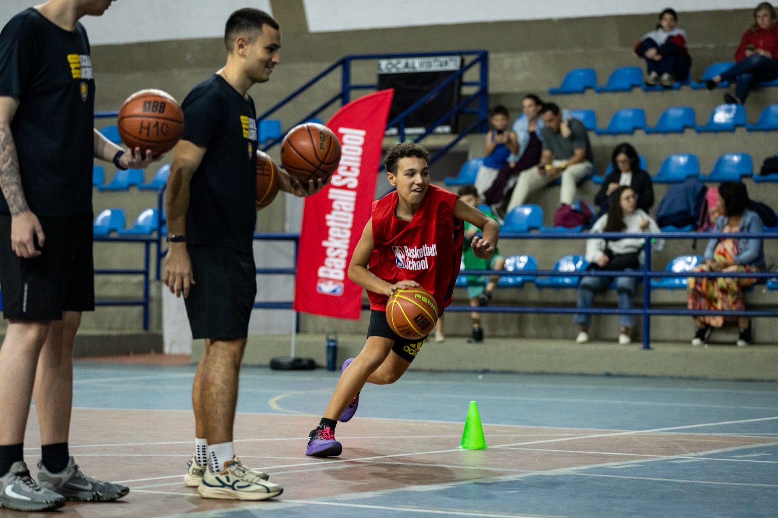Professor(a) da H10 cumprimentando o(a)s aluno(a)s com um high-five na quadra de basquete